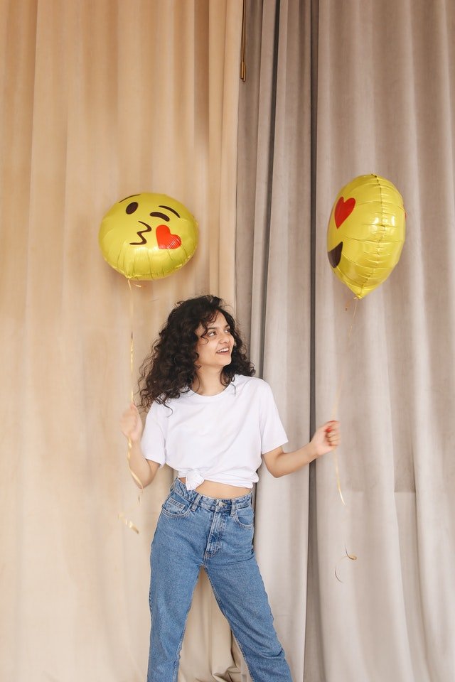 smiling young lady holding balloons while standing near 3905903